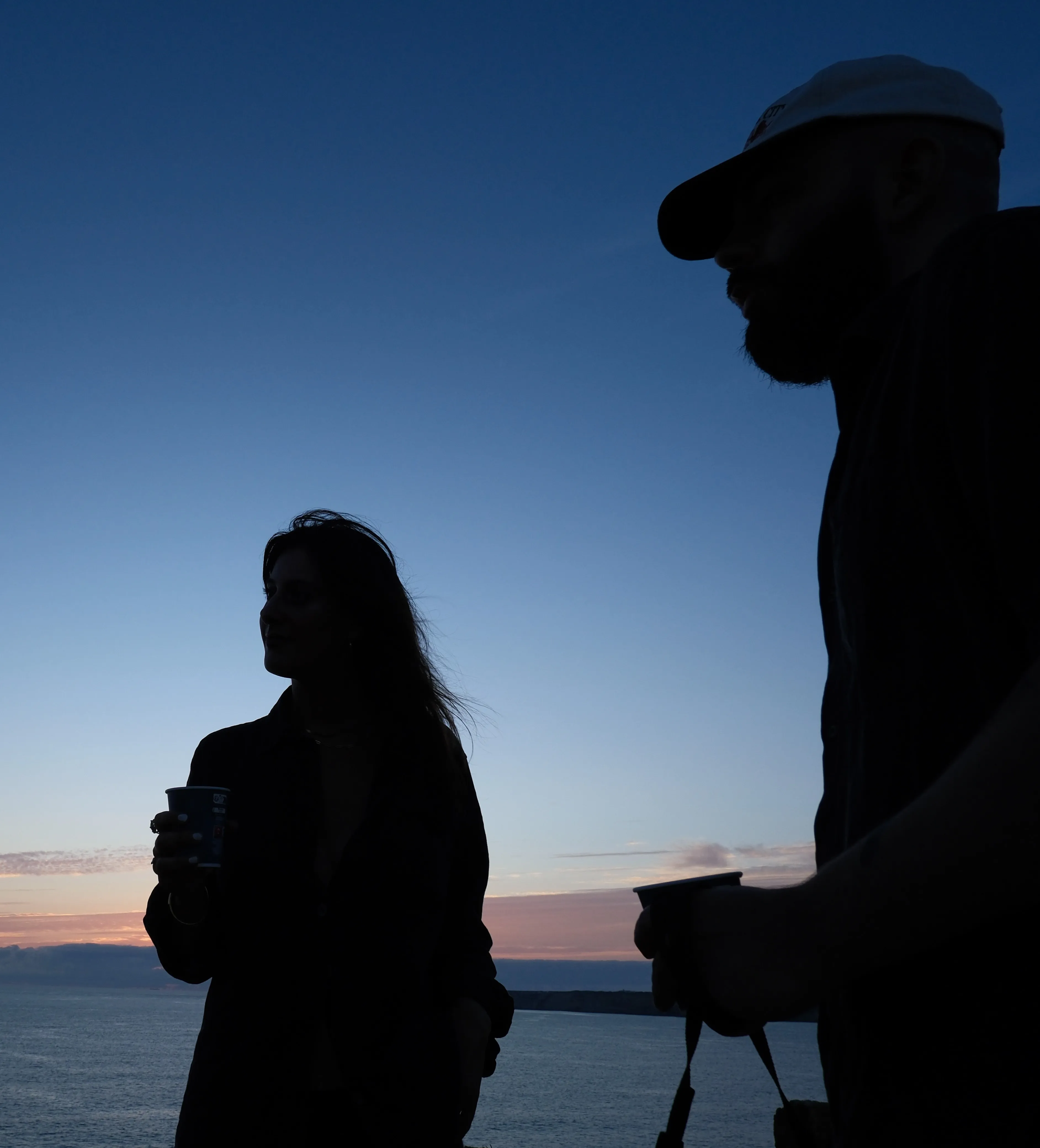 Two silhouettes against the evening sky by the sea